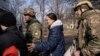 FILE - Olga Shulga and her son Myroslav board a van during an evacuation by Ukrainian police, in Avdiivka, Ukraine, March 7, 2023. 