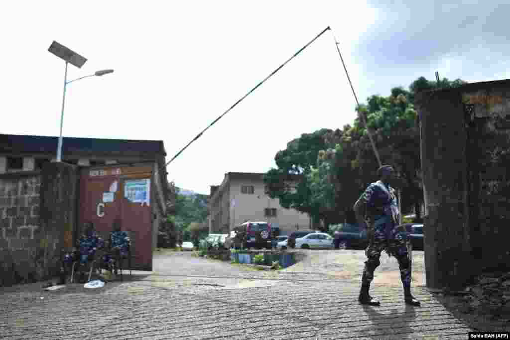 Membros das forças policiais da Serra Leoa na entrada da Sierra Leone Broadcasting Corporation em Freetown, a 27 de novembro de 2023, após confrontos que abalaram a capital Freetown, a26 de novembro de 2023. (Foto por Saidu BAH / AFP)