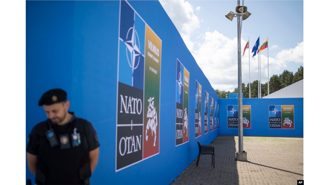 A security guard stands in front of a banner outside the venue of the NATO summit in Vilnius, Lithuania, July 9, 2023.