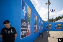 A security guard stands in front of a banner outside the venue of the NATO summit in Vilnius, Lithuania, July 9, 2023.