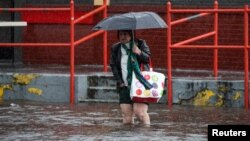 Uma mulher caminha através da chuva e das águas das cheias, no bairro de Brooklyn, em Nova Iorque, EUA, a 29 de setembro de 2023.
