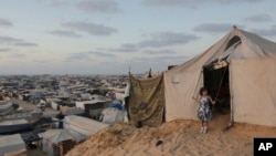A Palestinian girl stands at the entrance of her family tent at a makeshift tent camp for those displaced by the Israeli air and ground offensive on the Gaza Strip in Khan Younis, Gaza, June 18, 2024.