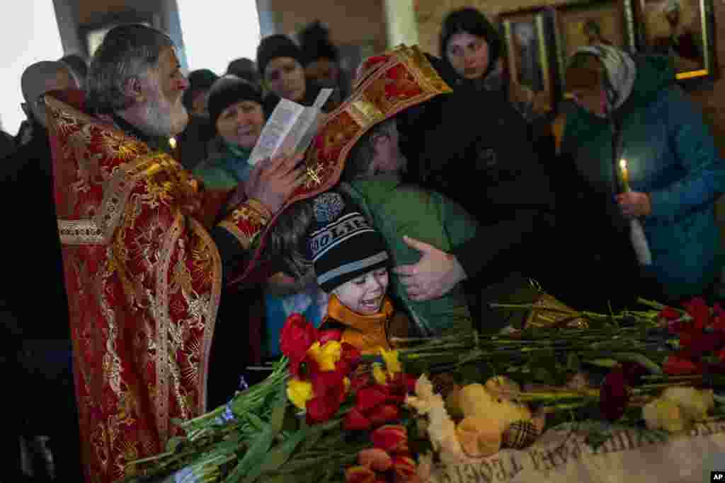 Mykhayl Shulha (centro) llora junto al ataúd de su hermana, Sofia Shulha, durante su funeral en Uman, en el centro de Ucrania, el 30 de abril de 2023. Sofia Shulha, de 11 años, murió en un ataque a un edificio residencial durante la guerra con Rusia. (AP Foto/Bernat Armangue).