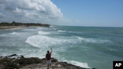 A man takes a video from the rocky shore of Mirador beach ahead of Hurricane Beryl's expected arrival, in Tulum, Mexico, July 4, 2024.