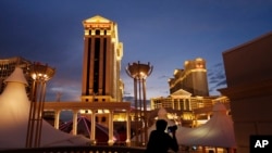 FILE - A man takes pictures of Caesars Palace hotel and casino in Las Vegas, Jan. 12, 2015.