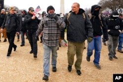 FILE - Proud Boys including Joseph Biggs, front left, walk toward the U.S. Capitol in Washington, Jan. 6, 2021.