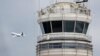 ARCHIVO - Un avión de pasajeros vuela frente a la torre de control de la FAA en el Aeropuerto National Ronald Reagan de Washington, el jueves 24 de marzo de 2011.