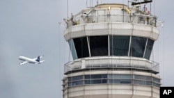 ARCHIVO - Un avión de pasajeros vuela frente a la torre de control de la FAA en el Aeropuerto National Ronald Reagan de Washington, el jueves 24 de marzo de 2011.