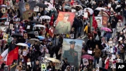 FILE - People attend the Immortal Regiment march through the main street toward Red Square marking the 77th anniversary of the end of World War II, in Moscow, Russia, May 9, 2022. 