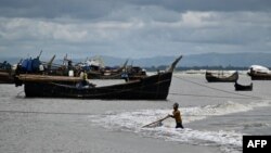 কক্সবাজার সমুদ্র সৈকতে একটি মাছ ধরার ট্রলারের সামনে মাছ শিকার করছে এক জেলে। (ফাইল ছবি) 