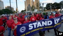 FILE - United Auto Workers members, including President Shawn Fain, center, march past General Motors headquarters in Detroit, Michigan, Sept. 15, 2023.