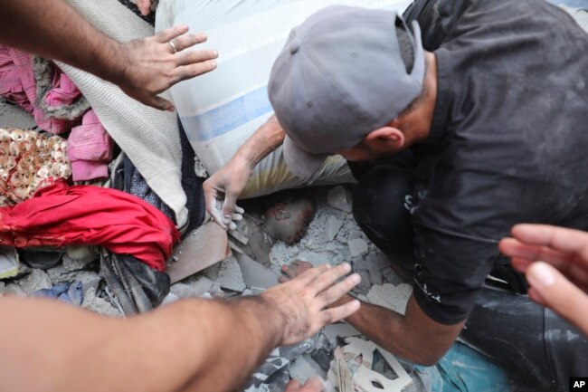 Palestinians try to pull out a child after the Israeli bombardment of the Gaza Strip in the Nusseirat refugee camp, Oct. 24, 2023.