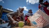 FILE - An Ethiopian woman scoops up portions of wheat to be allocated to each waiting family after it was distributed by the Relief Society of Tigray in Agula, in the Tigray region of northern Ethiopia, May 8, 2021. 