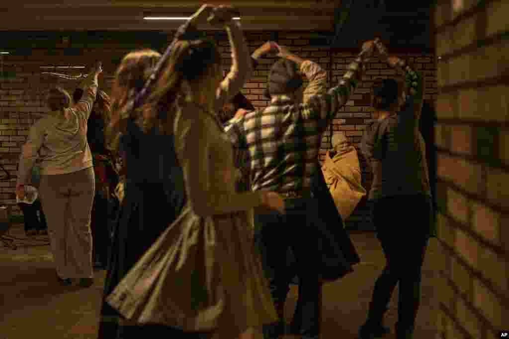 Una mujer mayor, cubierta por una manta, mira mientras varias personas bailan en una estación de metro luego de que sonaron las alarmas antiaéreas, en Kiev, Ucrania, el 1 de marzo de 2023. (AP Foto/Vadim Ghirda). Entre el cansancio por la guerra y las tensiones físicas y emocionales que superan las familias, Ucrania se encuentra en una situación delicada. Pero a pesar de la tristeza, hay momentos para la alegría.