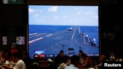 北京市民在一个餐馆里吃饭期间餐馆电视屏幕播放中国海军山东号航母参加东部战区军演的新闻。（2023年4月10日）