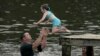 John Crouch membantu seorang anak perempuan berenang untuk mendinginkan tubuh dari cuaca panas di Ross Barnett Reservoir di Bobby Cleveland Park, Lakeshore di Rankin County, Mississippi, Jumat, 30 Juni 2023. (Foto: Rogelio V. Solis/AP)