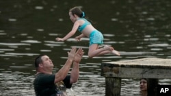 John Crouch of Richland, helps Phoebe Sheffield, 5, dive into the Ross Barnett Reservoir at Bobby Cleveland Park at Lakeshore in Rankin County, Miss., as residents seek ways to beat the heat, June 30, 2023.