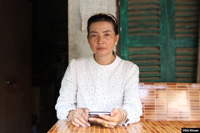 អ្នកស្រី ឡង់ សូដានី ភរិយារបស់លោក ខឹម ចាន់ វណ្ណៈ អង្គុយខាងមុខបន្ទប់ស្នាក់នៅក្នុងសង្កាត់និងមើលរូបស្វាមីដែលកំពុងជាប់ពន្ធនាគារ ក្នុងសង្កាត់កាកាបទី១ ខណ្ឌពោធិ៍សែនជ័យ កាលពីថ្ងៃទី៨ ខែកុម្ភៈ ឆ្នាំ២០២៤។ (លាស់ លីបលីប/វីអូអេ)