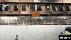 在内罗毕，行人走过在反对肯尼亚财政法案的示威活动期间一座被焚烧的商厦。(2024年6月28日)