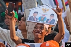 Pendukung calon presiden Anies Baswedan dan pasangannya Muhaimin Iskandar bersorak menunggu kedatangan pasangan tersebut untuk mendaftarkan nama mereka untuk mencalonkan diri pada pemilu tahun depan di gedung KPU Jakarta, 19 Oktober 2023. (Foto: AP )