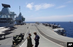 FILE - Military personnel participate in the NATO Steadfast Defender 2021 exercise on the deck of the aircraft carrier HMS Queen Elizabeth off the coast of Portugal, May 27, 2021.