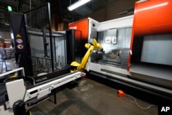 A Halter robot collects a finished piece for blood pressure pumps from a Mazak Integrex at Reata Engineering and Machine Works, Feb. 15, 2024, in Englewood, Colo.