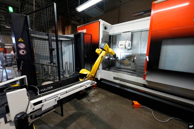 A Halter robot collects a finished piece for blood pressure pumps from a Mazak Integrex at Reata Engineering and Machine Works, Feb. 15, 2024, in Englewood, Colo.
