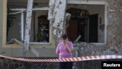 Жительница Львова разговаривает по телефону после удара российского беспилотника по окраине этого города (Украина, 19 июня 2024 года. REUTERS/Roman Baluk)