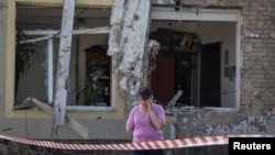 Жена зборува на мобилен телефон на местото на напад со руски дрон, на периферија во Лавов, Украина, 19 јуни 2024 година.