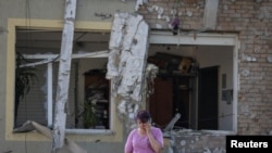 Seorang perempuan menelpon dari lokasi serangan pesawat tak berawak Rusia di pinggiran Lviv, Ukraina, di tengah serangan Rusia ke Ukraina, 19 Juni 2024. (REUTERS/Roman Baluk)
