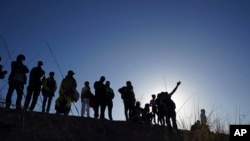 Migrantes observan desde el lado mexicano de la frontera mientras otros cruzan el Río Bravo hacia Estados Unidos desde Ciudad Juárez, México, el miércoles 29 de marzo de 2023, un día después de que decenas de migrantes murieran en un incendio en un centro de detención de migrantes en Ciudad Juárez.  (Foto AP/Fernando Llano)