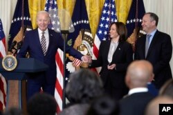 FILE - President Joe Biden holds hands with Vice President Kamala Harris as he speaks during a Black History Month reception in the East Room of the White House in Washington, Feb. 6, 2024.