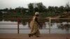 FILE - A woman crosses a bridge over the Mpoko River in Bangui, Central African Republic, March 13, 2014. A wooden ferry was carrying more than 300 people to a funeral over the Mpoko River in Bangui Friday when it started to collapse, according to witnesses.