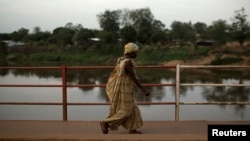 FILE - A woman crosses a bridge over the Mpoko River in Bangui, Central African Republic, March 13, 2014. A wooden ferry was carrying more than 300 people to a funeral over the Mpoko River in Bangui Friday when it started to collapse, according to witnesses.