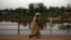 FILE - A woman crosses a bridge over the Mpoko River in Bangui, Central African Republic, March 13, 2014. A wooden ferry was carrying more than 300 people to a funeral over the Mpoko River in Bangui Friday when it started to collapse, according to witnesses.