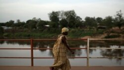 Une femme traverse le pont sur la rivière Mpoko le 13 avril 2024, RCA.