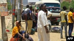 People wait for a bus to flee from southern Khartoum, Sudan, April 18, 2023, as fighting between the army and paramilitary forces led by rival generals rages for a fourth day.