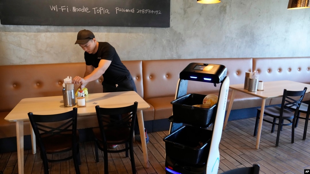 Ilustracija: Robot u restoranu Nudltopija se vraća u kuhinju nakon što je stol očišćen, Mičigen, 20.mart, 2023. (Foto: AP/Carlos Osorio)