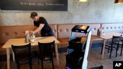 A robot helps clean up at the Noodle Topia in Michigan, March 20, 2023. (AP Photo/Carlos Osorio)