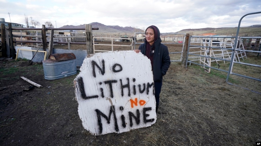 FILE - Daranda Hinkey, a Fort McDermitt Paiute and Shoshone tribe member, holds a sign that reads, 'No Lithium No Mine,' at her home on the Fort McDermitt Indian Reservation, April 24, 2023, near McDermitt, Nev.