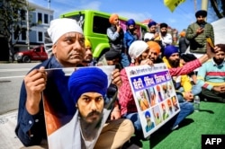 FILE - Raman Singh (L) holds a photo of Sikh organizer Amritpal Singh while protesting against the Indian government outside the Indian Consulate in San Francisco on March 20, 2023.