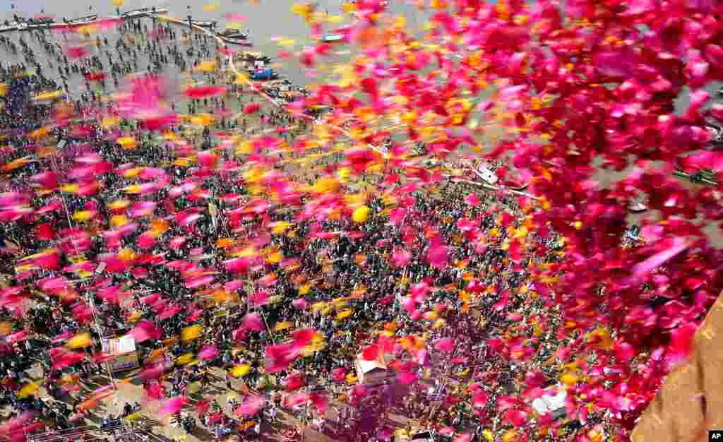 State government officials throw flowers from a helicopter as Hindu devotees throng Sangam, the confluence of the rivers Ganges and the Yamuna on Mauni Amavasya in Prayagraj, India.