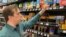 Stuart Dryden reaches for an item at a grocery store on Feb. 21, 2024, in Arlington, Va. Dryden is aware of big price disparities between branded products and their store-label competitors, which he now favors.