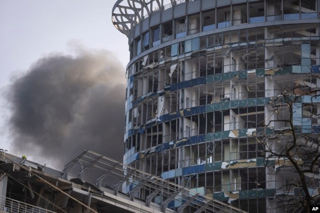 Asap mengepul di belakang bangunan yang rusak akibat serangan rudal Rusia di Kyiv, Ukraina, Jumat, 29 Desember 2023. (Foto: AP)