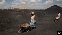 FILE - Women push wheelbarrows atop a coal mine dump at the coal-powered Duvha power station, near Emalahleni east of Johannesburg, Nov. 17, 2022. (AP Photo/Denis Farrell, File)
