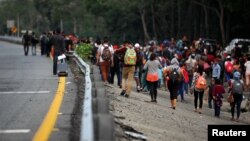 Migrantes cubanos caminan cerca de la carretera después de que las autoridades mexicanas confiscaran sus autobuses mientras participaban en el Vía Crucis Migrante para continuar su viaje hacia Estados Unidos, en Huixtla, México, el 17 de abril de 2019.