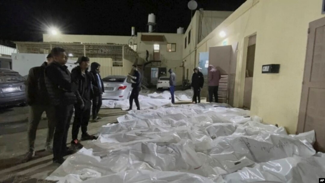 In this image from video, people look over some of the bodies which arrived at Al Aqsa hospital in Deir El Balah, Gaza on Sunday night, Dec. 24, 2023, after three strikes hit Central Gaza.