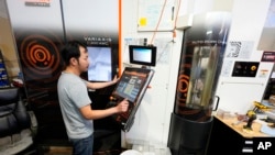 A worker at Reata Engineering and Machine Works programs a Mazak Variaxis machine used to make semiconductor pieces, Feb. 15, 2024, in Englewood, Colo. Reata has invested heavily in software that automates its manufacturing processes. 