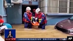 In this image taken from video footage run by China's CCTV, rescuers evacuate a resident following flooding in a village in eastern China's Zhejiang province, July 23, 2023. (CCTV via AP)