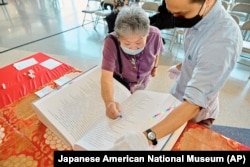 FILE - In this photo provided by the Japanese American National Museum, Barbara Keimi stamps the Ireichō at the Japanese American National Museum in Los Angeles, Sept. 24, 2022. T